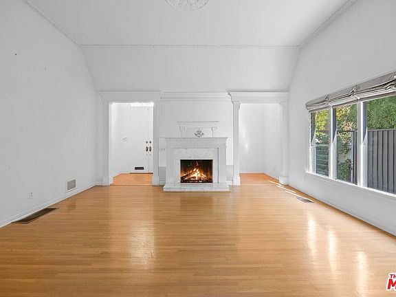The great room: vaulted ceiling, original mantel with carved frieze, working fireplace, oak floors running to a window seat.